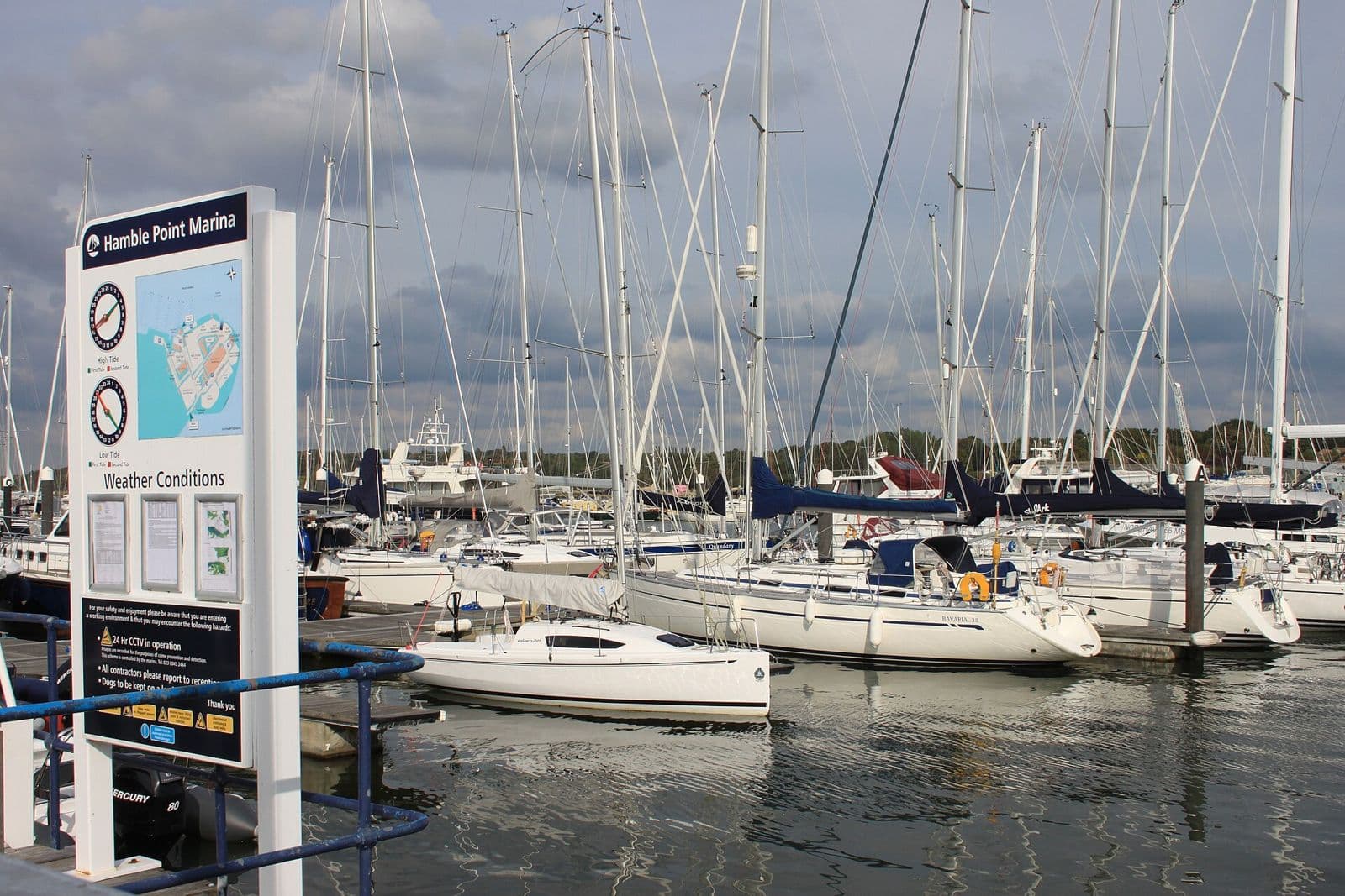 Yachts on their berths at Hamble Point Marina on the River Hamble, with the marina's information board on the pontoon